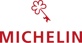Logo de Michelin composé du mot "MICHELIN" en lettres rouges et d'une fleur stylisée avec une clé à l'intérieur
