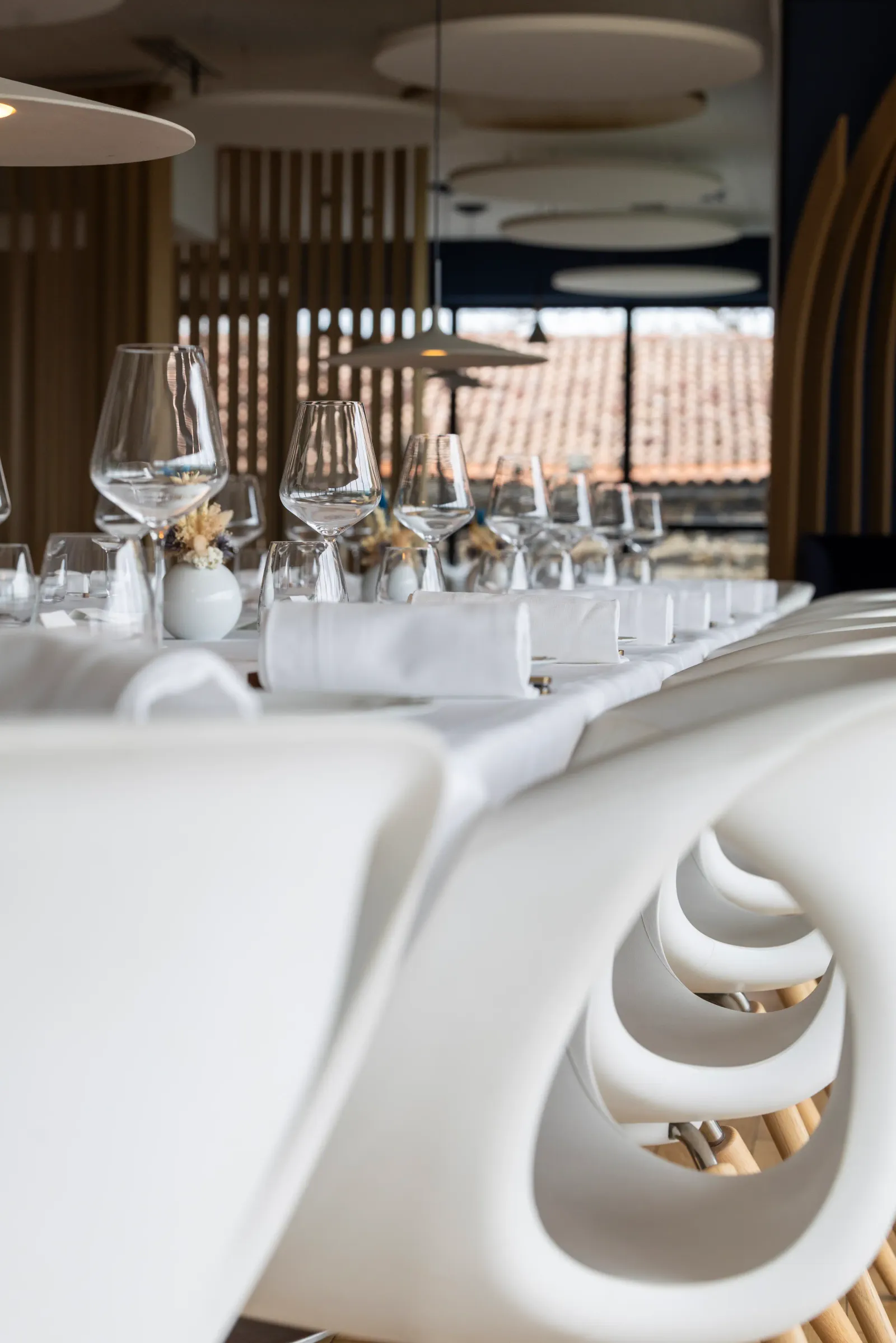 Table dressée avec verres à vin, couverts et serviettes en tissu dans un restaurant élégant avec vue sur des vignes