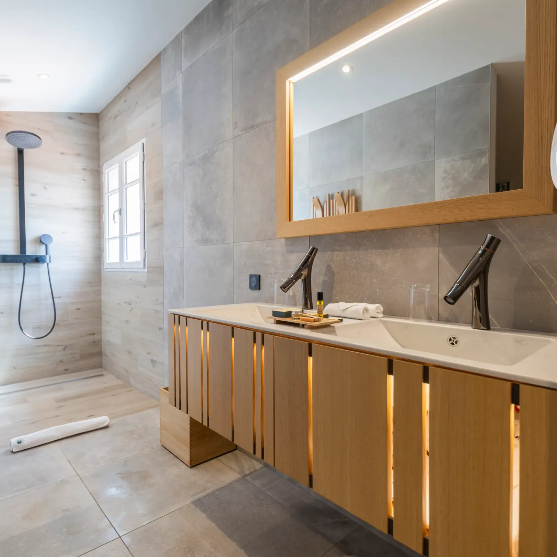 Salle de bain moderne avec douche à effet pluie, double vasque et miroir éclairé