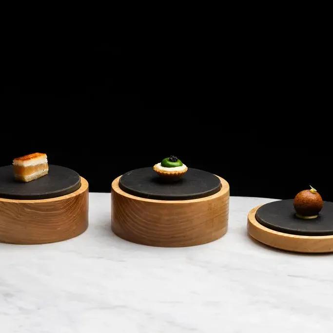 Trois petits plats en bois avec des aliments différents sur un plan de travail en marbre