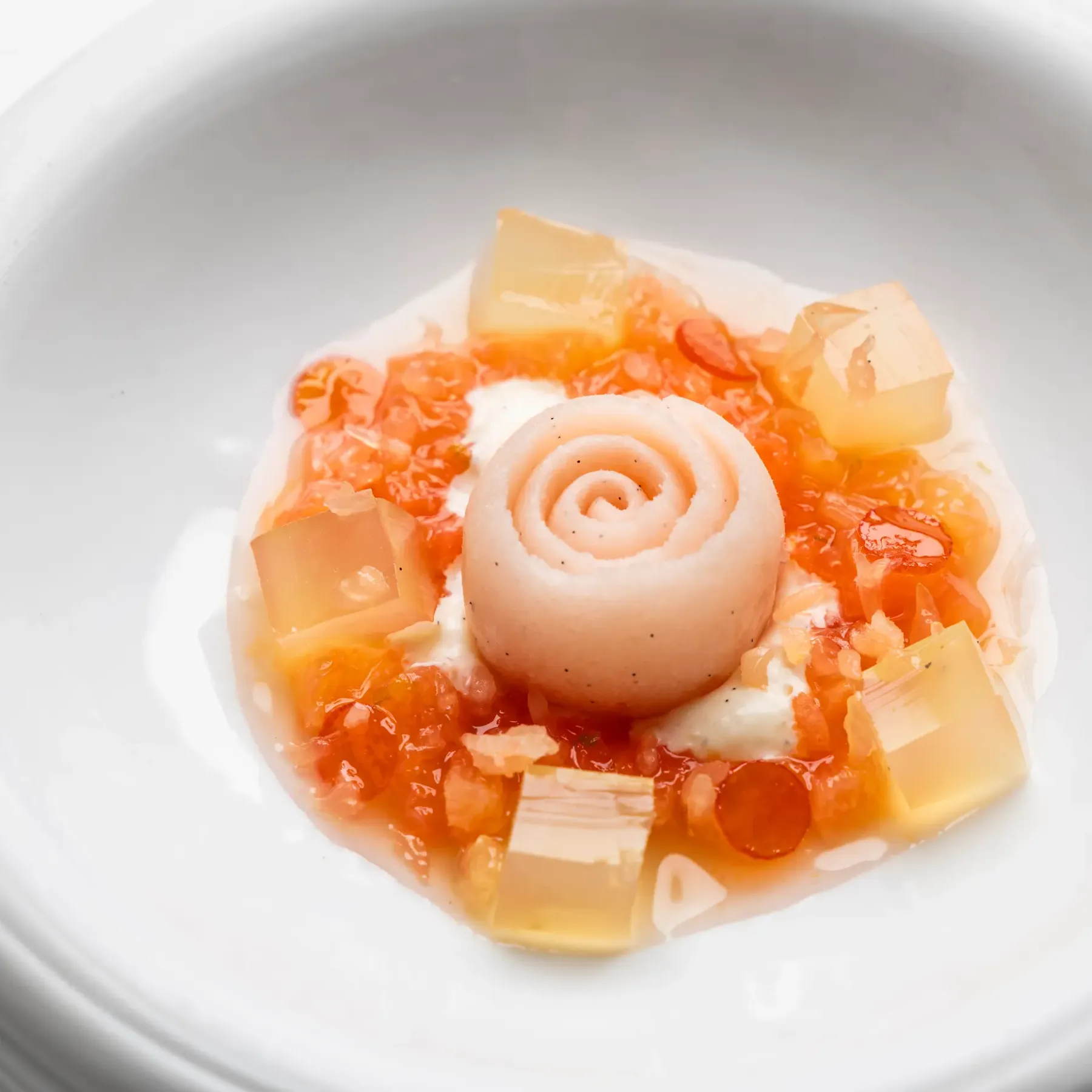 Un bol blanc contient une préparation culinaire avec des morceaux de légumes et une boule de pâte enroulée