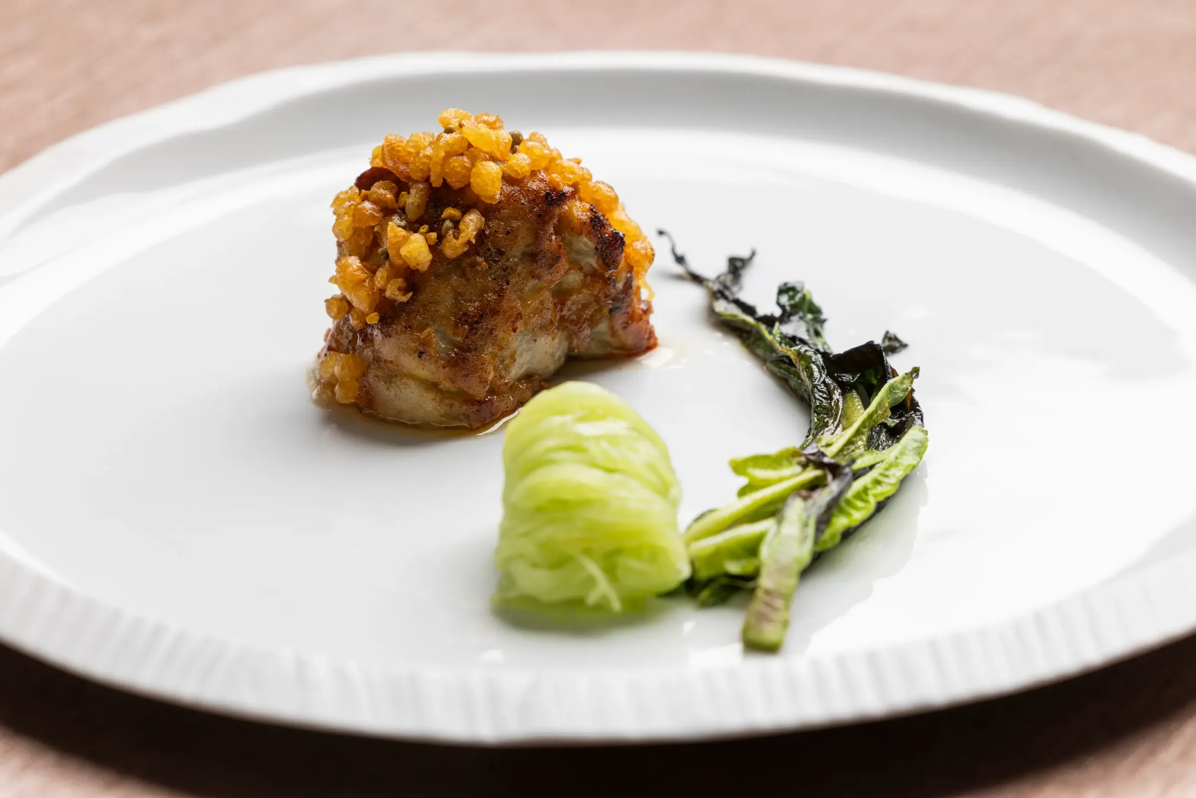 Un plat composé d'un morceau de viande croustillant, d'une purée verte et de légumes verts grillés